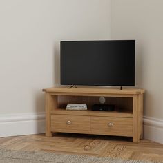 a flat screen tv sitting on top of a wooden entertainment center next to a wall