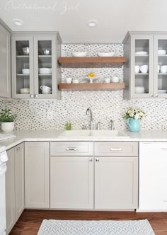 a kitchen with white cabinets and wooden shelves filled with dishes on top of the counters