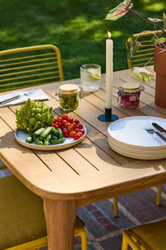 a wooden table topped with plates of food next to a candle and potted plant