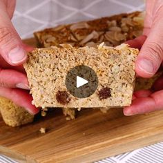 two hands holding a piece of bread with nuts and raisins on it, while another person holds out their hand to the camera