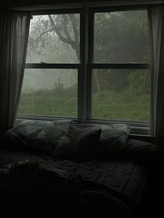 a bed sitting in front of a large window covered in foggy weather and trees