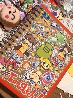 an open notebook with stickers on it and a stuffed animal sitting next to it