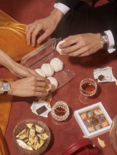 several people are sitting at a table with food and drinks on it, including wine glasses