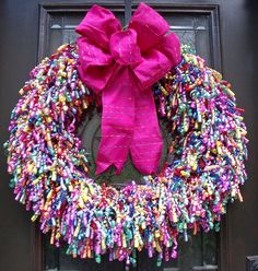 a wreath made out of candy sticks is hanging on the front door with a pink bow