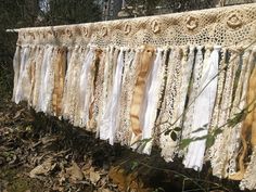 several pieces of lace hanging from a clothes line outside on the ground in front of some trees