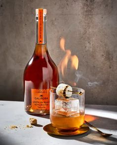 a bottle of alcohol sitting on top of a table next to a glass filled with liquid