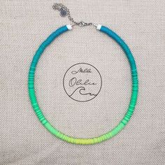 a green and blue beaded necklace on a white fabric background with the words meet me now written across it