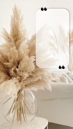 a vase filled with dry grass next to a white couch