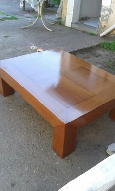 a wooden table sitting on top of a cement ground