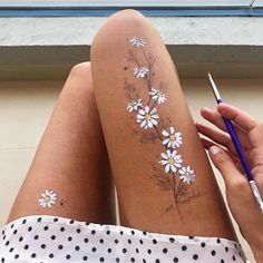 a woman with white flowers painted on her leg