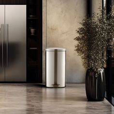 a kitchen scene with focus on the stainless steel refrigerator and trash can in the foreground