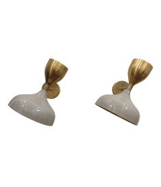 two white and gold wall sconces on a white background, one with a bow