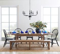 a dining room table with chairs and a bench in front of the window, next to a potted plant