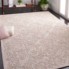 a large rug in the middle of a living room with two chairs and a potted plant