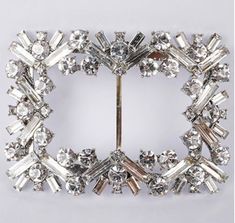 a silver brooch with crystal stones in the center and two rows of diamonds on each side