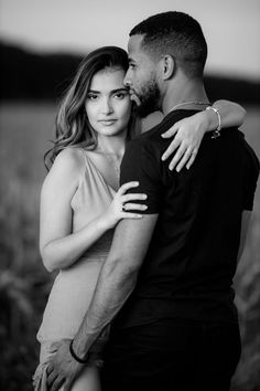 black and white photo of a couple embracing each other in the middle of a field