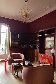 a living room filled with furniture and a chandelier hanging from the ceiling next to a window