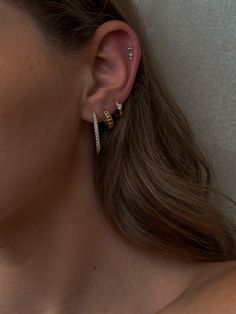 a close up of a person with ear piercings on their ears and behind them is a white wall