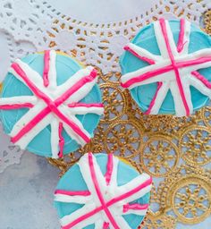 three decorated cupcakes with pink and white frosting on them sitting on a doily