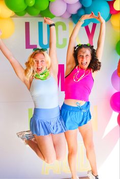 two young women jumping in the air with their arms up while wearing short skirts and high heels