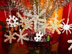 a christmas tree with snowflakes hanging from it's branches in front of a red wall