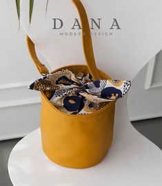 a yellow bucket bag sitting on top of a white chair