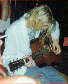 a woman with long blonde hair playing an acoustic guitar