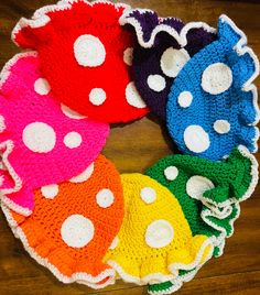 a colorful crocheted wreath with white polka dots on the top and bottom, sitting on a wooden floor