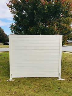 a white fence sitting in the grass next to a tree