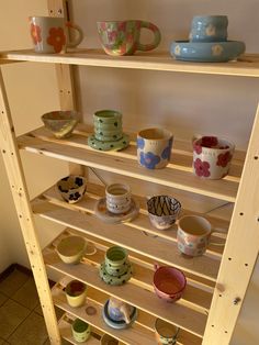 a shelf filled with cups and bowls on top of wooden shelves