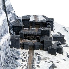 an aerial view of a building on a snowy mountain side with rocks and snow around it