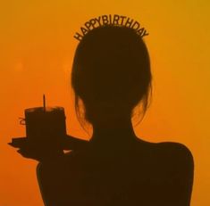 the silhouette of a woman holding a birthday cake in front of an orange sky with happy birthday written on it