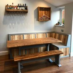 a wooden table and bench in a room with wood flooring next to a wine rack