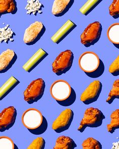 chicken wings, celery sticks, and other foods are arranged on a blue surface