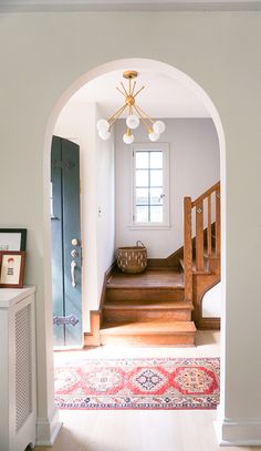 an archway leading to a hallway with a rug on the floor and stairs in front of it