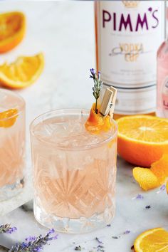 two glasses filled with pink lemonade and lavender sprig garnished with an orange slice