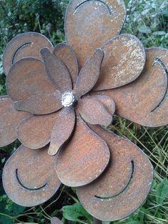 a large metal flower sitting on top of a lush green field