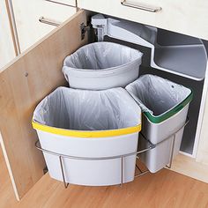 three trash cans in the corner of a kitchen cabinet