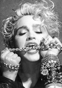 a woman with lots of bracelets on her face and hands over her mouth as if she is trying to break the chain