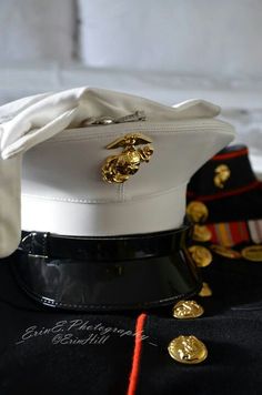 a white hat with gold buttons on it sitting on top of a black table cloth