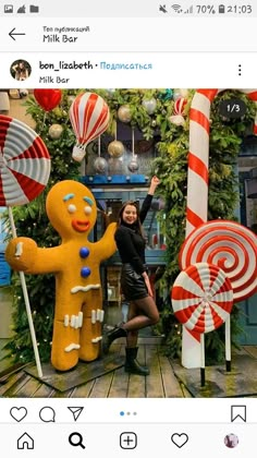 a woman standing in front of giant candy canes and gingerbread man statues on display