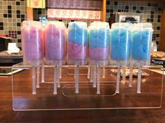 four different colored ice creams in plastic containers on a counter top with other items behind them