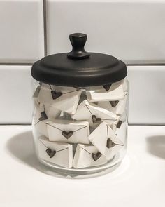 a glass jar filled with lots of white tiles