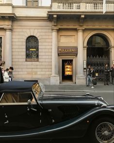 an old black car parked in front of a building