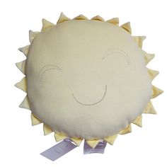 a white pillow with yellow spikes and a smiling face on it's front end