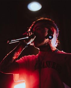 a man with headphones on holding a microphone to his ear while standing in front of a spotlight