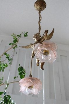 a chandelier with pink flowers hanging from it's sides and an angel figurine on top