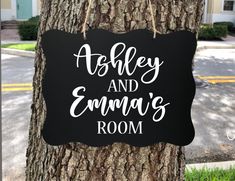 a sign that is on the side of a tree in front of a house and says ashley and emma's room