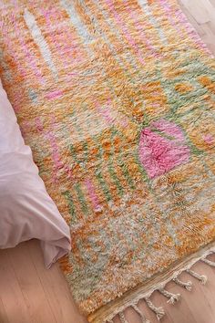 a colorful rug on the floor next to a bed