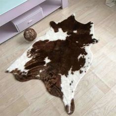 a brown and white cowhide rug sitting on top of a wooden floor next to a dresser